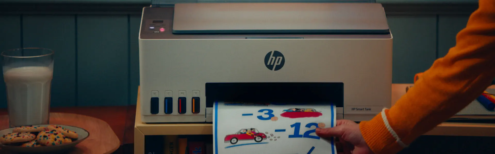 A child at a desk lit warmly beside an HP printer